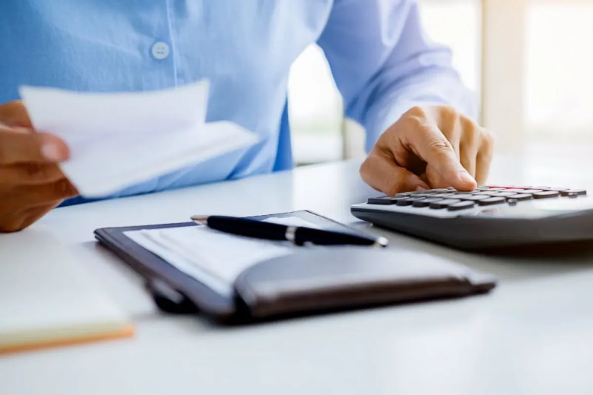 A man using calculator while holding a paper