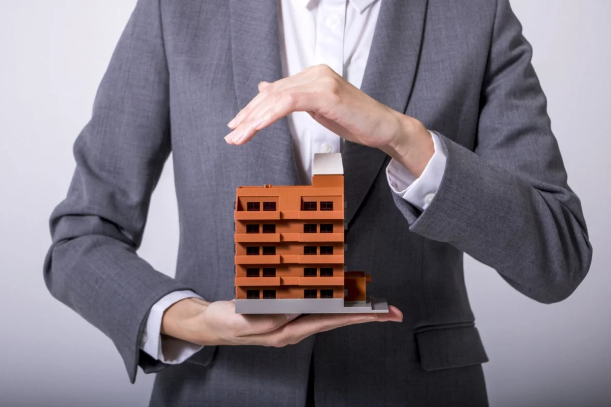 Businessperson holding miniature apartment building model