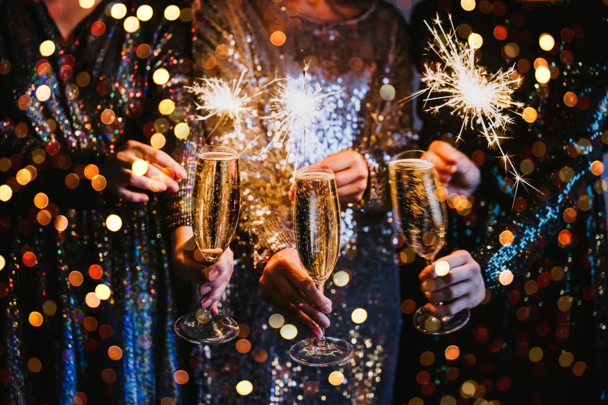 Friends celebrating Christmas or New Year eve party with Bengal lights and champagne.