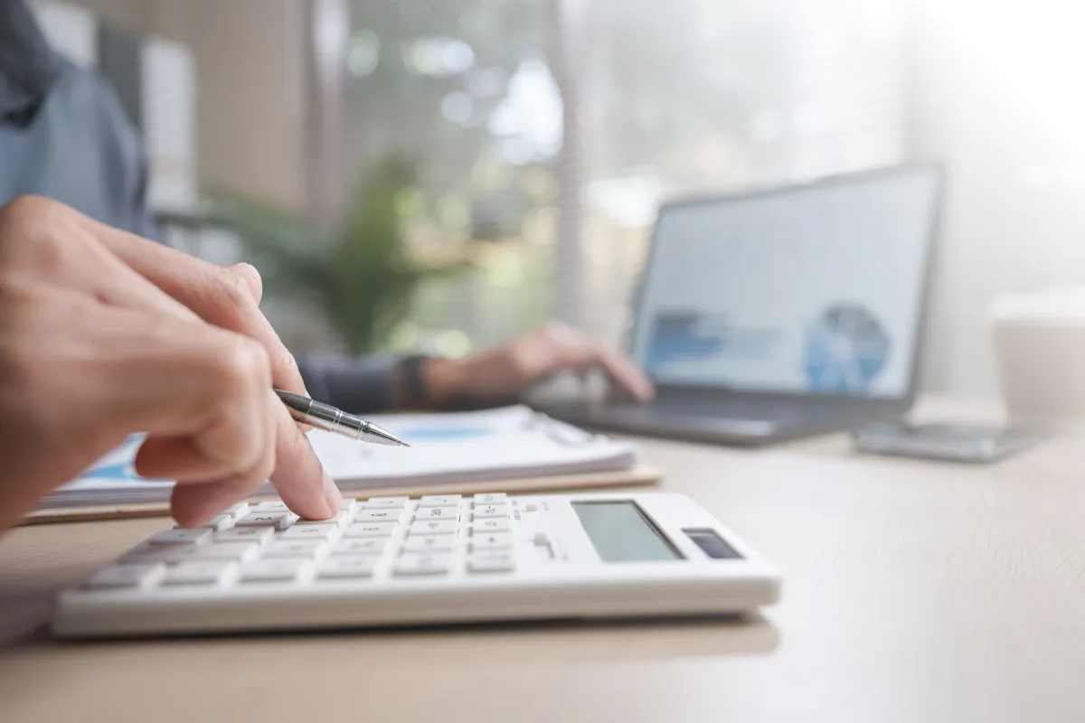 Person reviewing payment transaction and refund status using calculator and laptop.