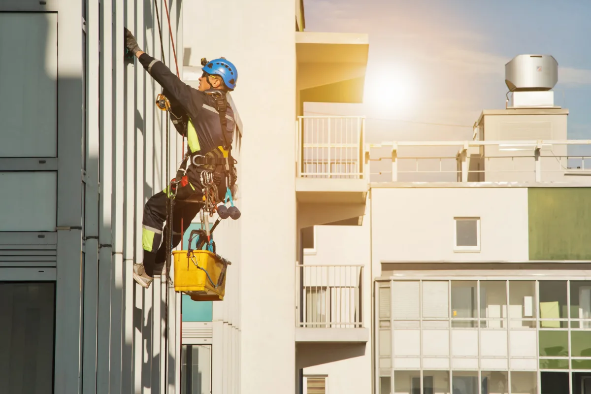Rope access technician carrying out external maintenance on a multi-storey strata apartment building.